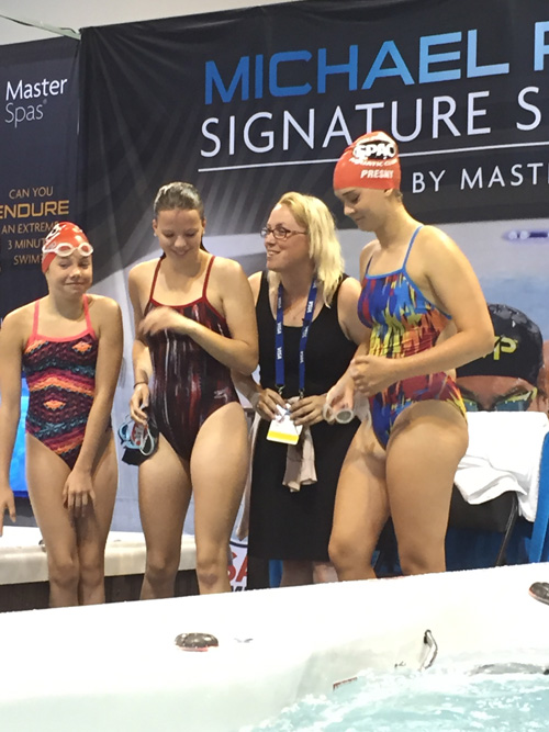 Heidi posing for photo with swimmers at swim trials in Omaha